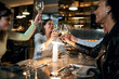 © Lomb - Multicultural smiling best friends toasting white wine at fusion bar restaurant
