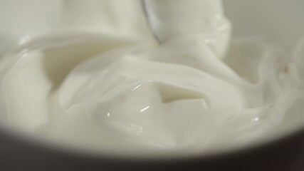 Wall Mural - Slow motion macro shot of swirling white yogurt with a spoon