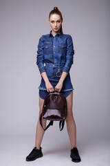 high fashion photo of a beautiful elegant young woman in a pretty denim jeans dress, black sneakers,