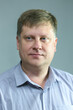 © ALEXEY - Portrait of a serious adult male blond 40 years old with a blue shirt on a black background.