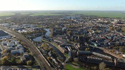 Wall Mural - 4k aerial video of historic village Woerden in the netherlands with trains driving by