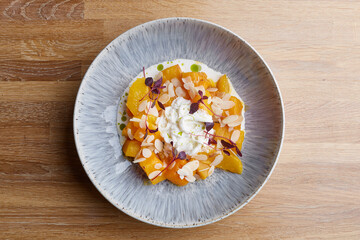 baked pumpkin in ceramic plate top view on wooden table with glass of white wine. pumpkin with stracciatella and microgreen