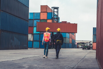 Wall Mural - Industrial worker works with co-worker at overseas shipping container yard . Logistics supply chain management and international goods export concept .