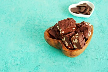 Wall Mural - Sliced homemade fudge chocolates made from dark chocolate, condensed milk and hazelnuts on a turquoise concrete background. Candy recipes. American cuisine.