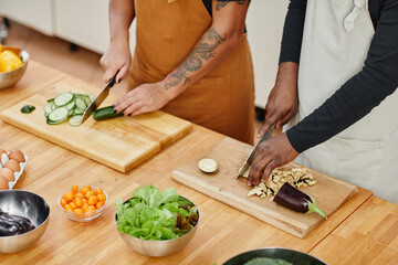 Wall Mural - High angle close up of two people cutting vegetables while cooking together in kitchen, copy space