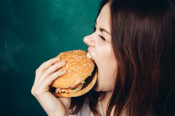 Wall Mural - woman eating hamburger fast food snack close-up