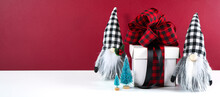Christmas Farmhouse Black Red And White Plaid Check Gnomes And Gift Against A Modern Red Maroon Background. Sized For Extra Wide Web And Social Media Banner Wioth Copy Space.