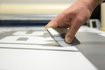 Close-up of a man's hand holding a trowel and preparing to make car stickers on vinyl