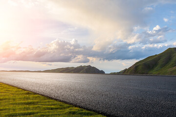 Wall Mural - Asphalt road and mountain scenery at sunrise. Highway and mountain background.