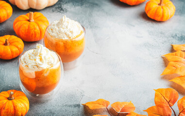 Wall Mural - Pumpkin latte coffee with wipper cream in glass cups on gray table. Autumn or winter hot drink in festive table setting