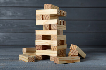 Wall Mural - Jenga tower and wooden blocks on grey table. Board game