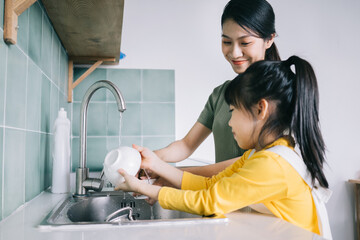 Canvas Print - Mother and daughter wash the dishes together.