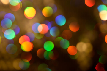 Wall Mural - Abstract colorful glowing iridescent drops and sparkles on a brown background. Rainbow bokeh backdrop or overlay. Blurred defocused circles.