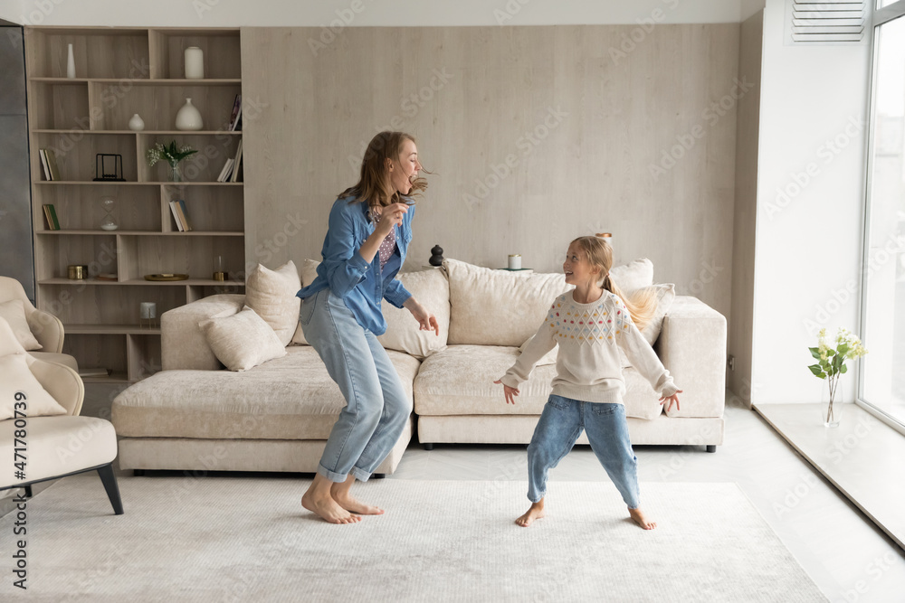 Happy emotional young mother or babysitter dancing to disco music ...