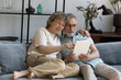 © fizkes - Happy elder 60s family couple with digital device relaxing on sofa together. Middle aged husband and wife using online app on tablet for internet shopping, virtual order, communication