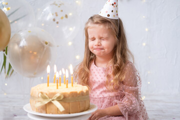 cute little child girl blowing candles on birthday cake and celebrating birthday