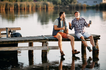 Cheerful senior father and his son talk during their fishing day in nature.