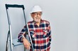© Krakenimages.com - Handsome mature handyman close to construction stairs wearing hardhat winking looking at the camera with sexy expression, cheerful and happy face.