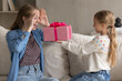 © fizkes - Happy young mother opening eyes, feeling excited of getting wrapped gift box from loving little kid daughter, surprised by prepared present, enjoying celebrating birthday or International Women's Day.