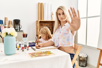 Canvas Print - Caucasian family of mother and daughter painting at art studio with open hand doing stop sign with serious and confident expression, defense gesture