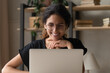 Good work. Positive smiling latina woman wear glasses sit by desk use laptop engaged in web search of information write blog online. Happy young female chat at internet read good news at social media