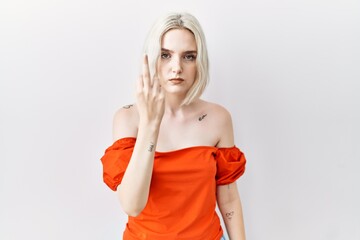 Sticker - Young caucasian woman standing over isolated background showing middle finger, impolite and rude fuck off expression