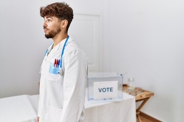 Sticker - Young arab doctor man at political election by ballot looking to side, relax profile pose with natural face with confident smile.