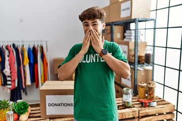 Poster - Young arab man wearing volunteer t shirt at donations stand laughing and embarrassed giggle covering mouth with hands, gossip and scandal concept