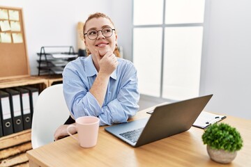 Sticker - Young redhead woman working at the office using computer laptop with hand on chin thinking about question, pensive expression. smiling and thoughtful face. doubt concept.