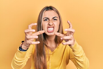 Canvas Print - Beautiful hispanic woman wearing casual yellow sweater shouting frustrated with rage, hands trying to strangle, yelling mad