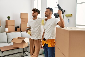 Two hispanic men couple smiling confident repairing house at new home