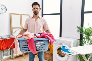 Poster - Young man with beard holding laundry basket skeptic and nervous, frowning upset because of problem. negative person.