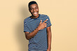 © Krakenimages.com - Young african american man wearing casual striped t shirt smiling cheerful pointing with hand and finger up to the side