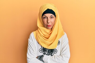 Poster - Middle age hispanic woman wearing traditional islamic hijab scarf skeptic and nervous, disapproving expression on face with crossed arms. negative person.