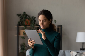Using tablet pc. Confident user young latin female scroll web pages on wide screen of pad device read business message on modern gadget. Millennial hispanic woman engaged in distant learning on tab