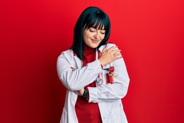 Poster - Young hispanic woman wearing doctor uniform and stethoscope hugging oneself happy and positive, smiling confident. self love and self care