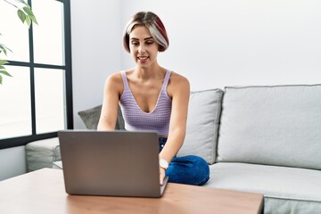 Sticker - Young caucasian girl using smartphone sitting on the sofa at home.