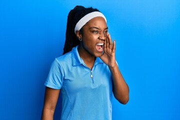 Poster - African american woman with braided hair wearing tennis player uniform shouting and screaming loud to side with hand on mouth. communication concept.