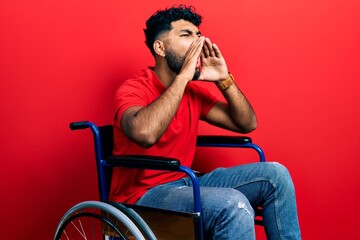 Canvas Print - Arab man with beard sitting on wheelchair shouting angry out loud with hands over mouth