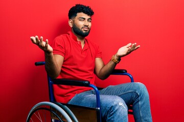 Canvas Print - Arab man with beard sitting on wheelchair clueless and confused with open arms, no idea concept.