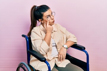 Poster - Young hispanic woman sitting on wheelchair pointing to the eye watching you gesture, suspicious expression