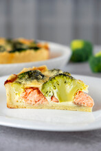 Open faced salmon and broccoli quiche on kitchen table with broccoli pieces and savory pie on background. Recipe of homemade fish pie of Mediterranean cuisine. Healthy eating or low card diet.