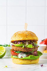 Wall Mural - Cooking vegan burger with avocado, tomato and peanut sauce, white background with ingredients.