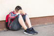© stivog - Lonely boy sitting alone on the ground, isolated from his peers, hiding