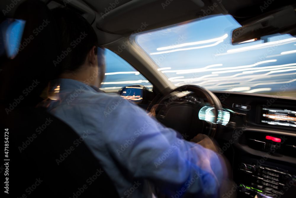 Driving a car at night - young man driving his modern car at night in a ...