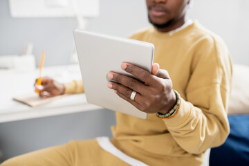 Aufkleber - Hand of young contemporary student holding tablet while making notes during online lesson in home environment