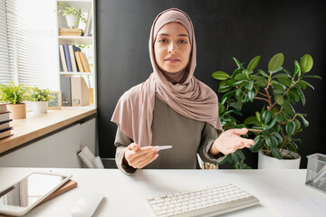 Poster - Young confident woman in hijab explaining subject to student while sitting in front of computer during online lesson