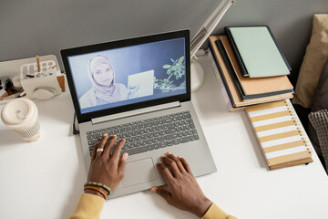 Aufkleber - Laptop on desk with teacher in hijab on the screen during online lesson and hands of African male student over keypad