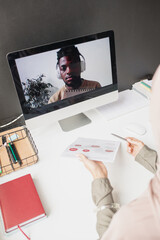 Poster - African guy with headphones on computer screen looking at teacher explaining data on paper during online lesson