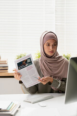 Sticker - Young Muslim female teacher in hijab pointing at financial document while making presentation during online lesson